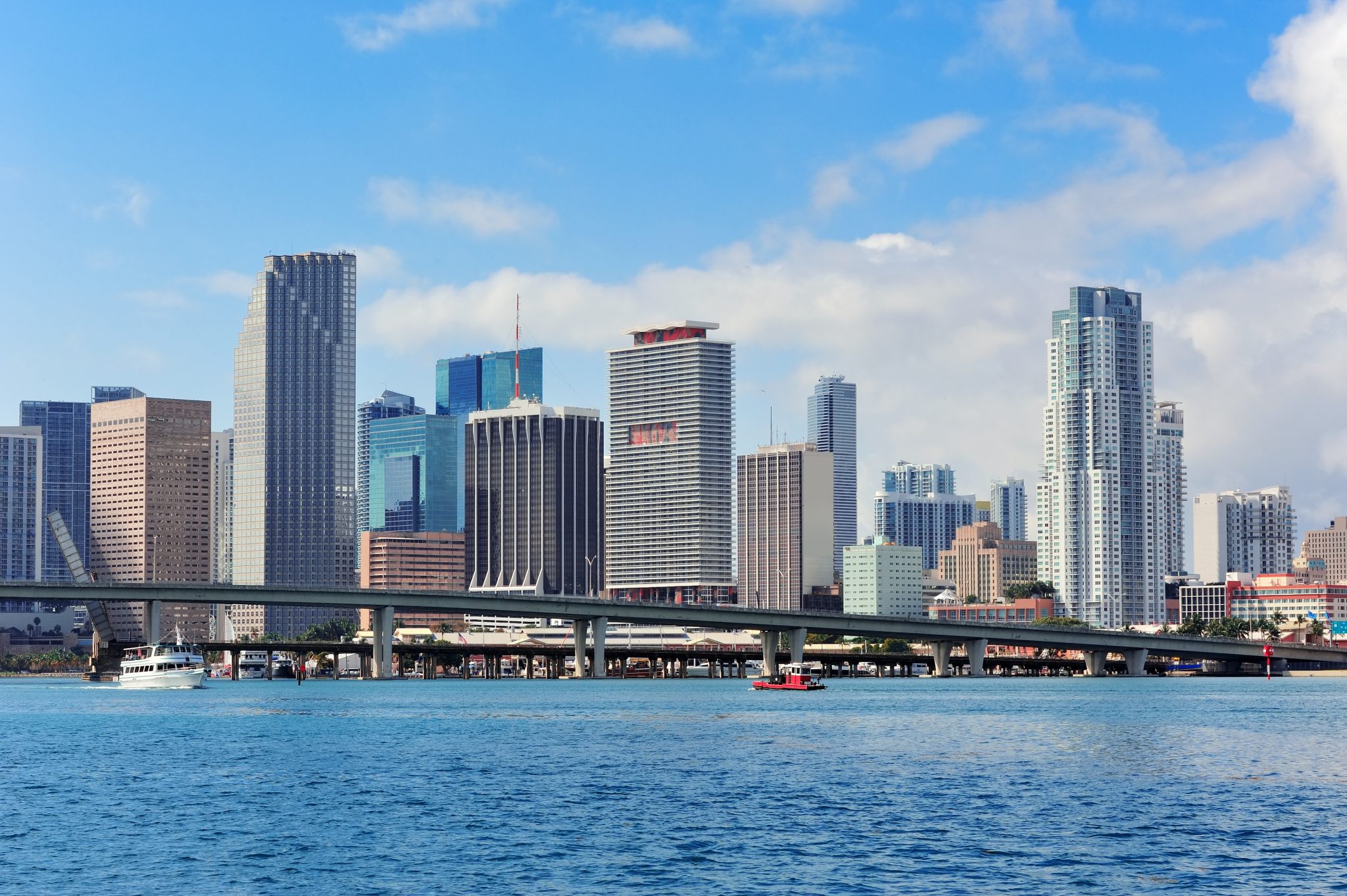 Miami skyscrapers with bridge over sea in the day.